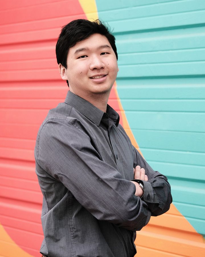 David Ganger, smiling with arms crossed, in front of a colorful mural